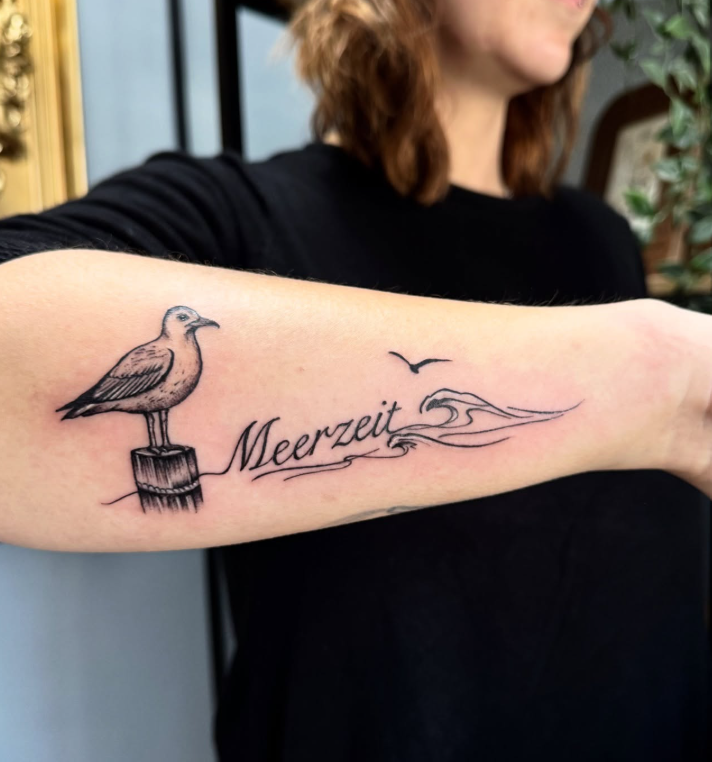 Fineline Möwe mit Welle und Schriftzug Meerzeit am Unterarm
