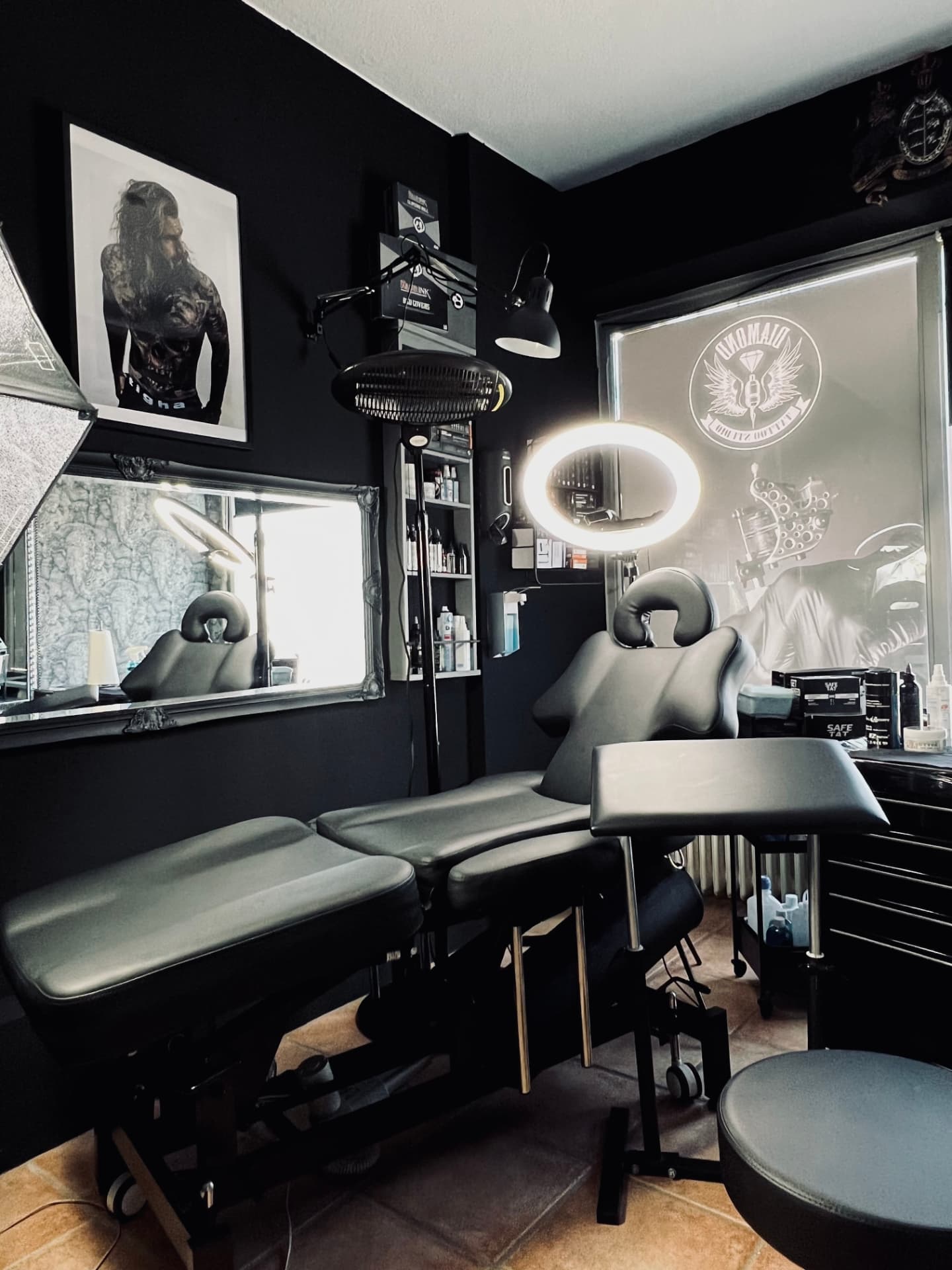 Mattschwarzer Tattoo-Behandlungsraum mit Ringlicht und Studio-Logo