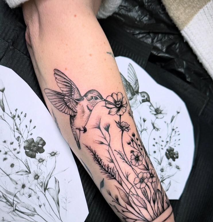 Kolibri mit Wildblumen als feines Black & Grey Tattoo am Unterarm