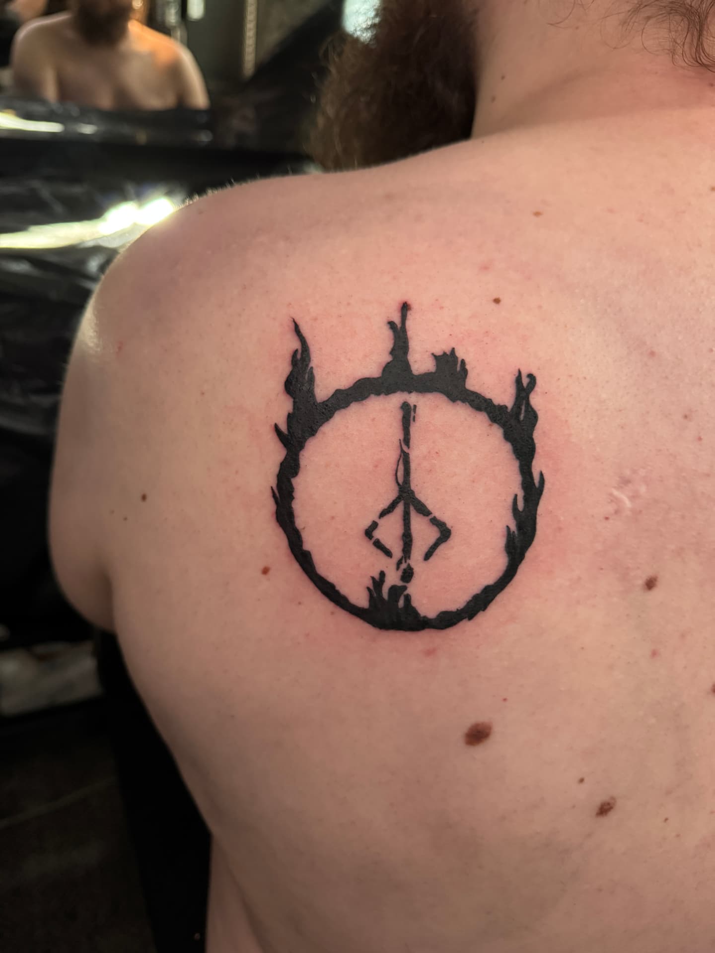 Blackwork Peace-Zeichen im Flammenkreis auf der Schulter
