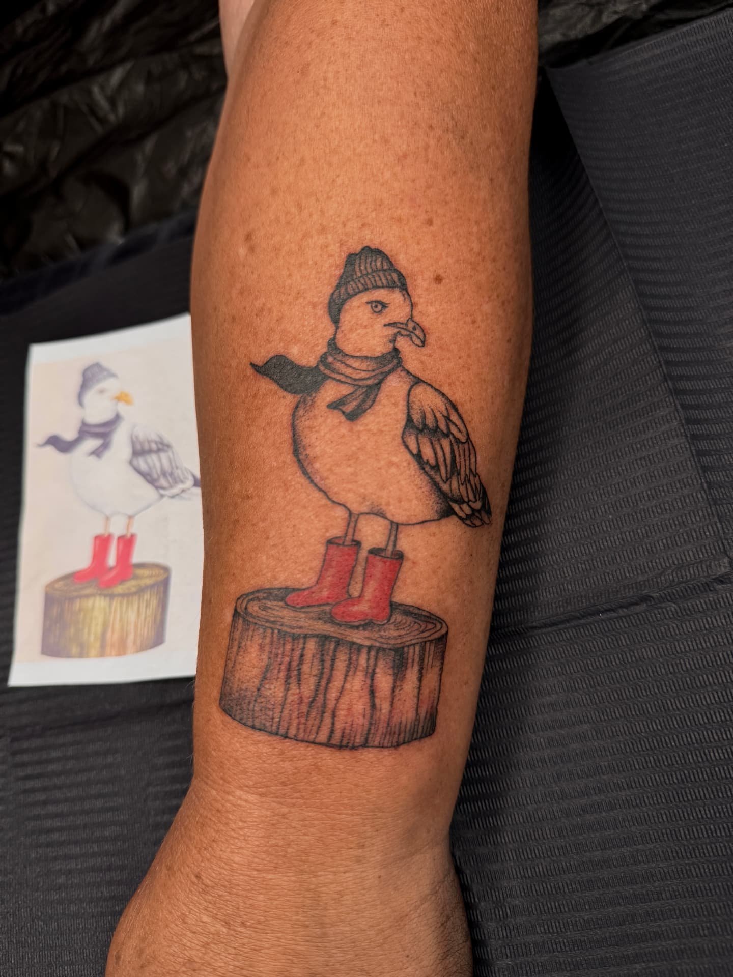 Möwe mit Mütze und roten Gummistiefeln auf Holzstumpf am Unterarm